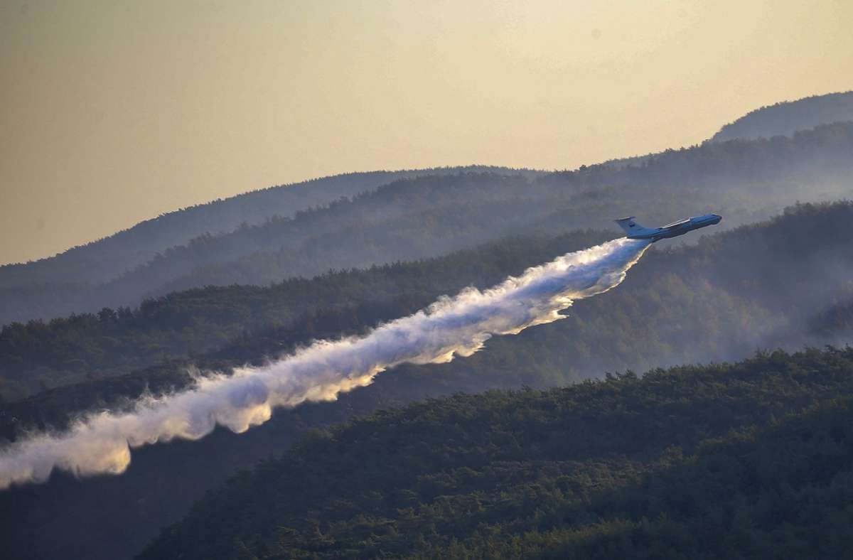 Ein Löschflugzeug der türkischen Streitkräfte wirft über einem Waldbrand in der Provinz Mugla im Süden der Türkei Wasser ab.