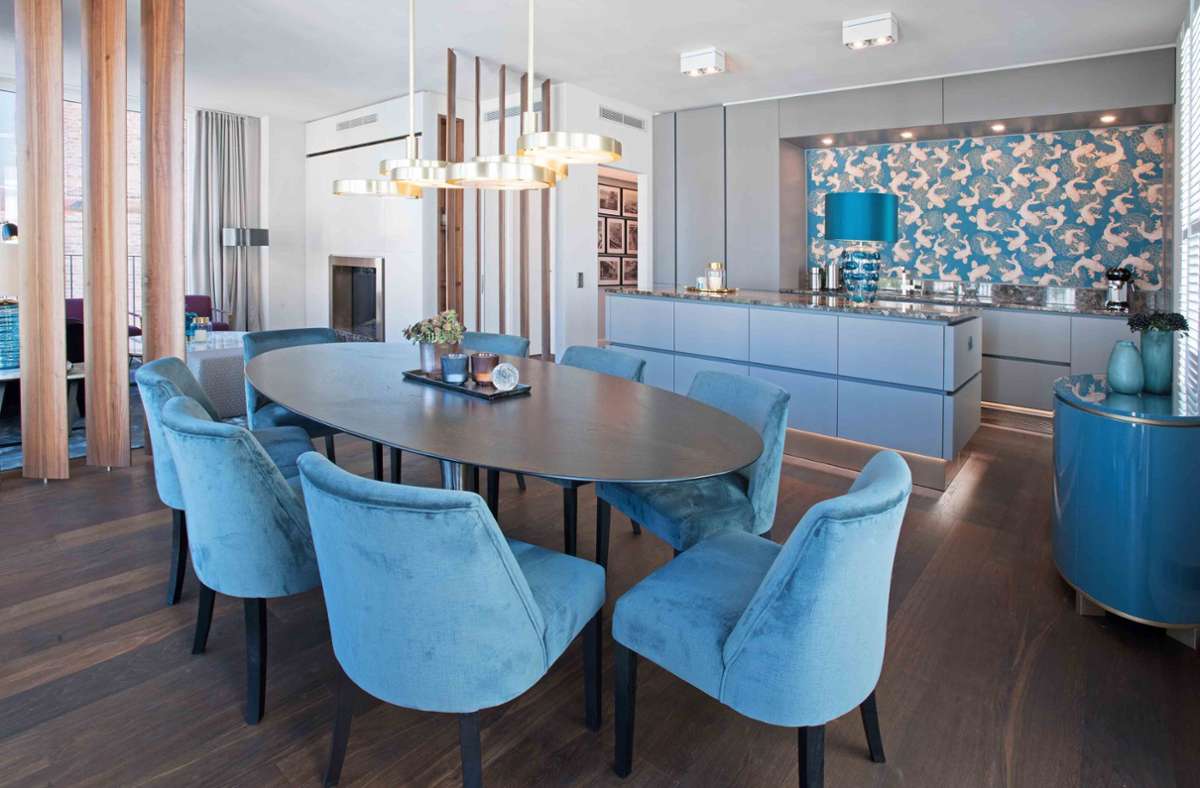Häufig sind Einbauküchen weiß – in dieser Berliner Wohnung nahe des Brandenburger Tores wurde Mut zur Farbe auch bei der hellblauen Küche bewiesen – passend zu den opulenten Stühlen am Esstisch – gestaltet von Julia Korzilius.
