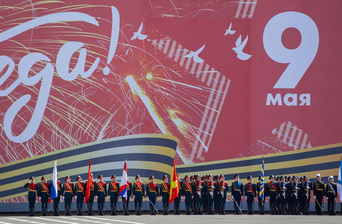 Russische Soldaten stehen während der Generalprobe für die Parade zum Tag des Sieges auf dem Palastplatz neben einer Mauer mit einem Banner, auf dem „9. Mai“ steht.