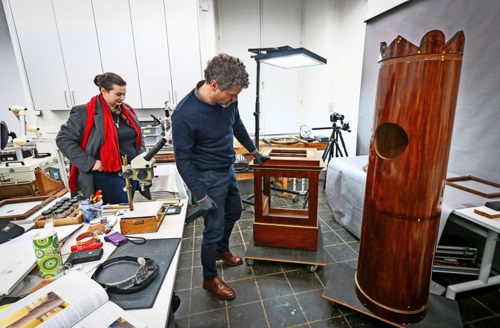 Die Restauratoren Frank Dornacher und Patricia Peschel inspizieren die Teile der 200 Jahre alten Uhr. Foto: factum/Granville
