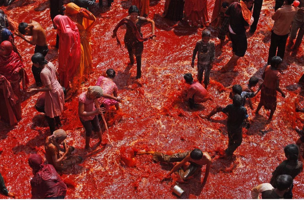 Indien: Indische Kinder spielen in einer Meer aus rotgefärbtem Wasser. Dieses Ritual gehört  zum Fest der Farben, das im Dauji Tempel südlich von Neu-Delhi gefeiert wird. Foto: AP