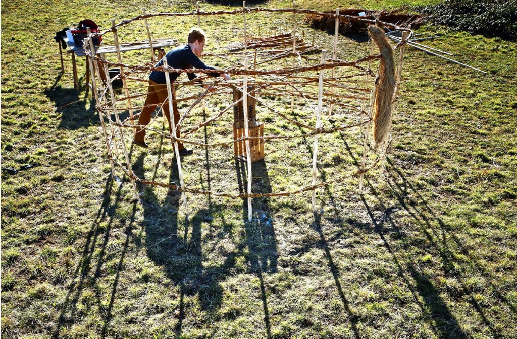 Noch liegt das Sonnenrad von David Klopp auf dem Boden, damit er besser daran arbeiten kann. Die Naturskulptur wird vier Meter hoch sein. Foto: Gottfried Stoppel
