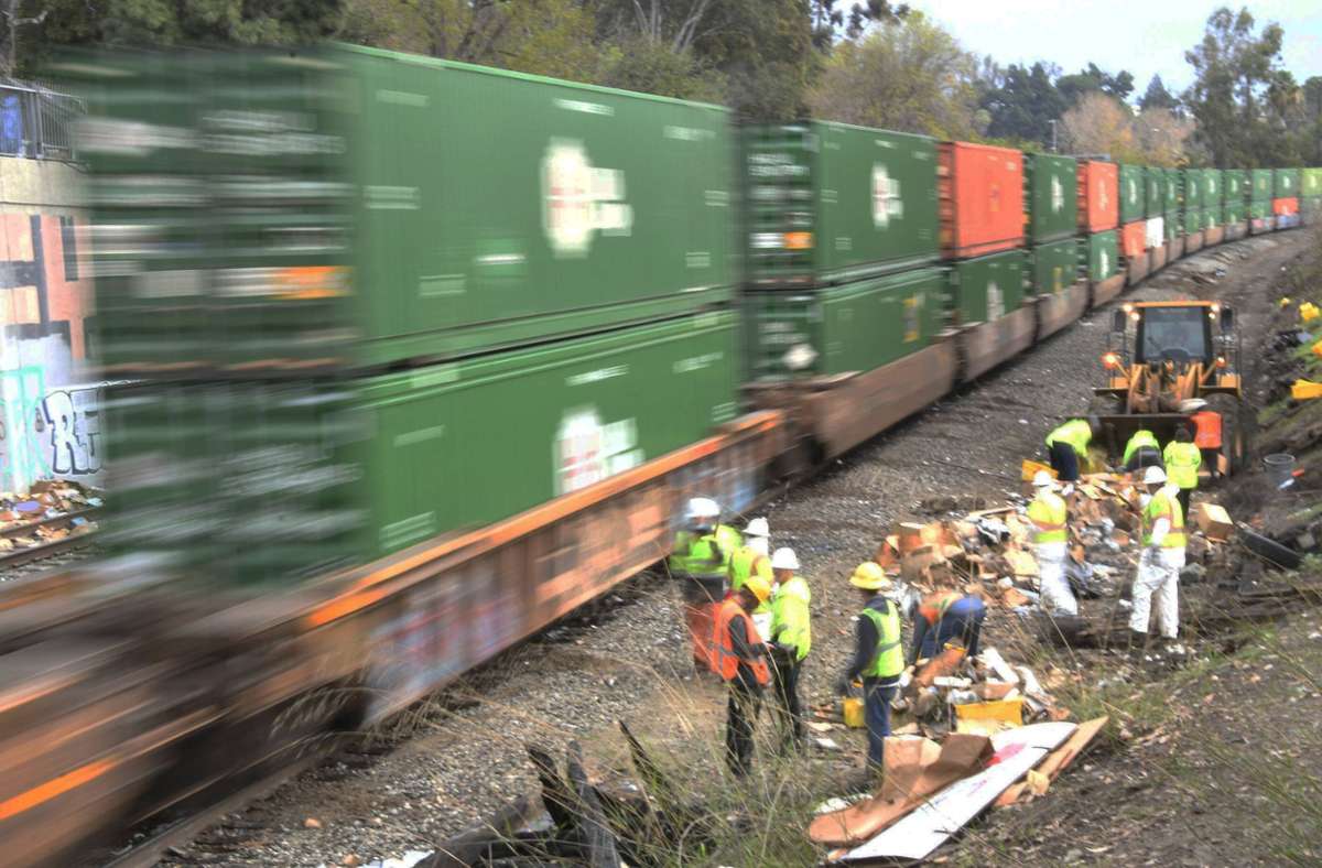 Ein Frachtzug der Union Pacific fährt in Los Angeles an einer Crew vorbei, die aufgerissene Paketen aufräumt, die Plünderer zurückgelassen haben.