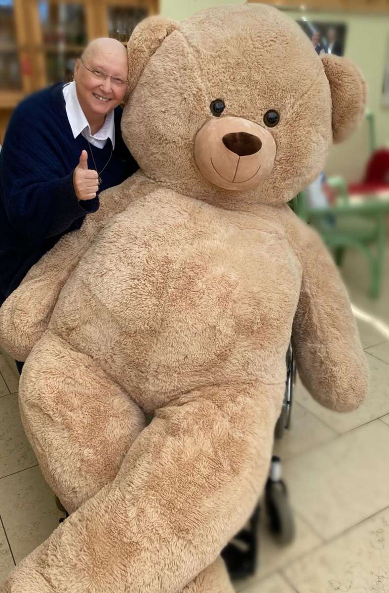 Die Patientin bekommt einen Riesen-Teddy geschenkt. Der Bär wird zugunsten der Initiative „Mit Krebs leben“ verlost, binnen drei Wochen kommen 18 000 Euro zusammen.