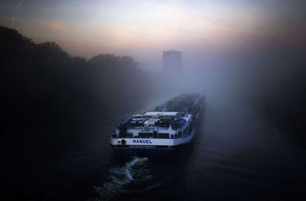 Nordrhein-Westfalen, Oberhausen: Ein Binnenschiff fährt bei Nebel auf dem Rhein-Herne-Kanal am Gasometer vorbei.