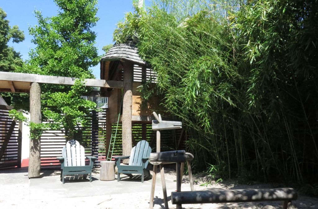Meterhohe Bambuspflanzen rahmen den Spielplatz ein. Im Hintergrund steht das Baumhaus, das genug Platz für Erwachsene und Kinder bietet.