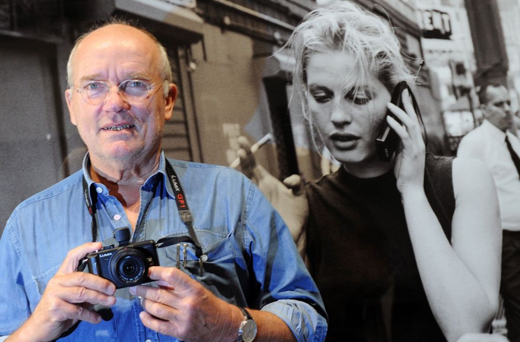 Der Modefotograf Peter Lindbergh steht mit einer Kamera in den Händen vor einer seiner Fotografien.