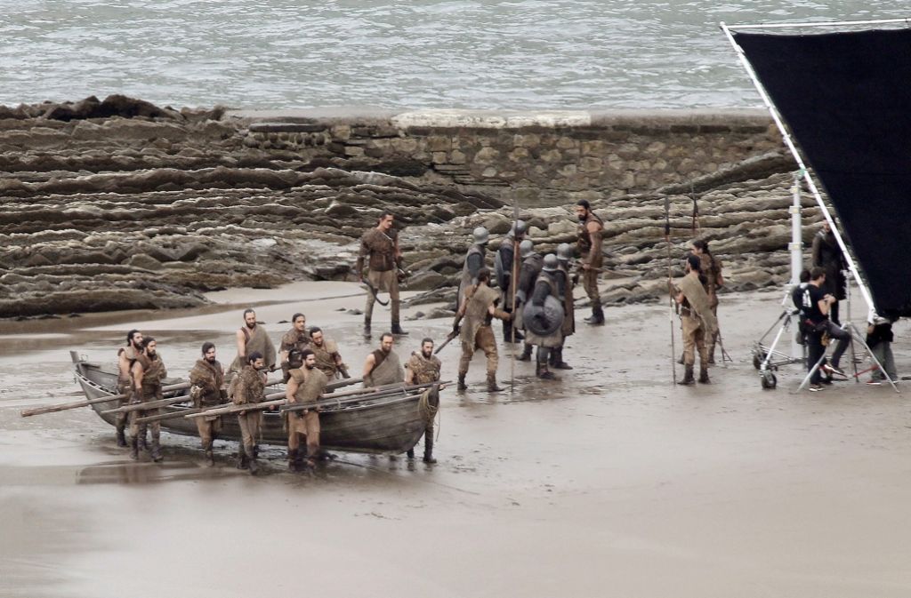 Dothraki tragen ein Holzboot ans Ufer.
