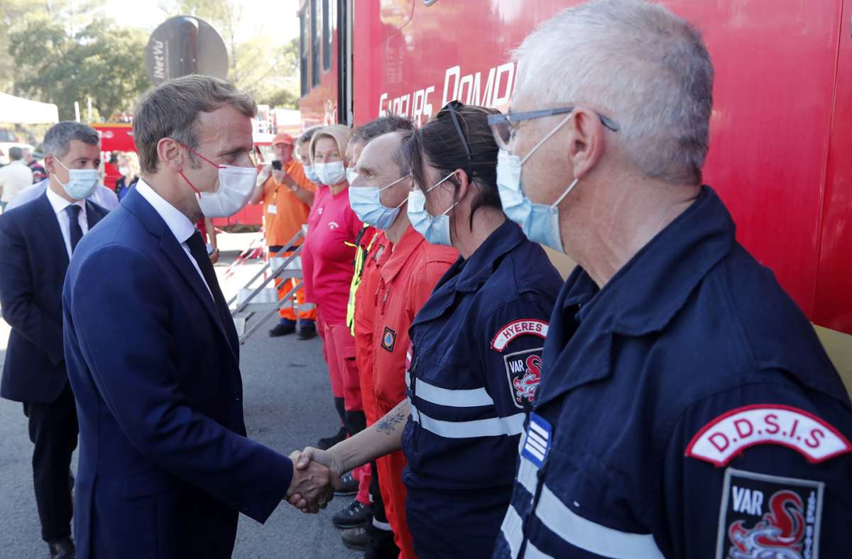 Emmanuel Macron (vorne links), Präsident von Frankreich, trifft Feuerwehrleute in Südfrankreich. Tausende Anwohner und Touristen haben sich vor weiter ausdehnenden Waldbränden in Südfrankreich in Sicherheit gebracht.
