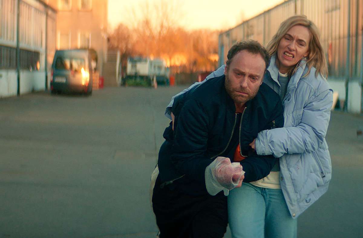 Die Prostituierte Camilla (Kim Riedle, re.) hilft Karow beim Ermitteln, sie war mit Maik gut befreundet. Sie schleppt den verletzten Robert Karow (Mark Waschke, li.) zum Auto. Szene aus „Das Opfer“, der „Tatort“ aus Berlin (Sendung vom 18. Dezember 2022).