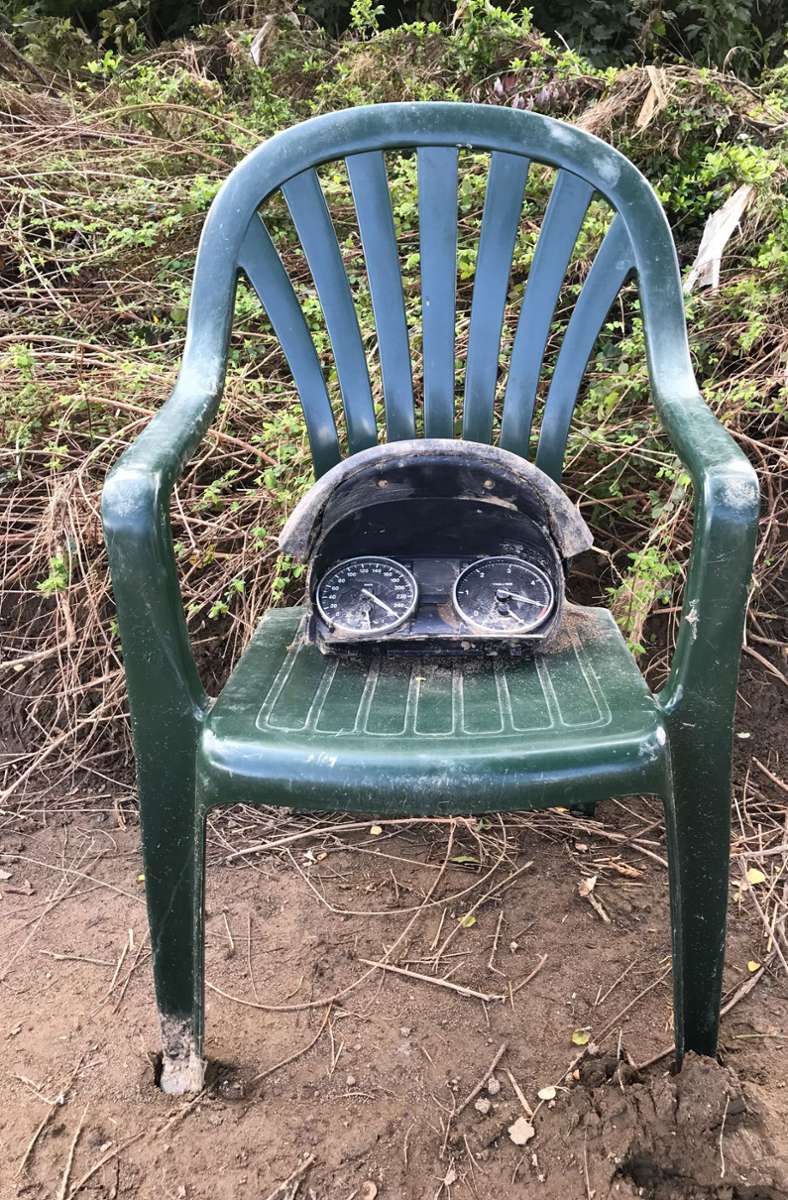 Verstörendes Stillleben: Überreste eines Tachometers aus einem Fahrzeug liegen auf einem angeschwemmten Gartenstuhl.