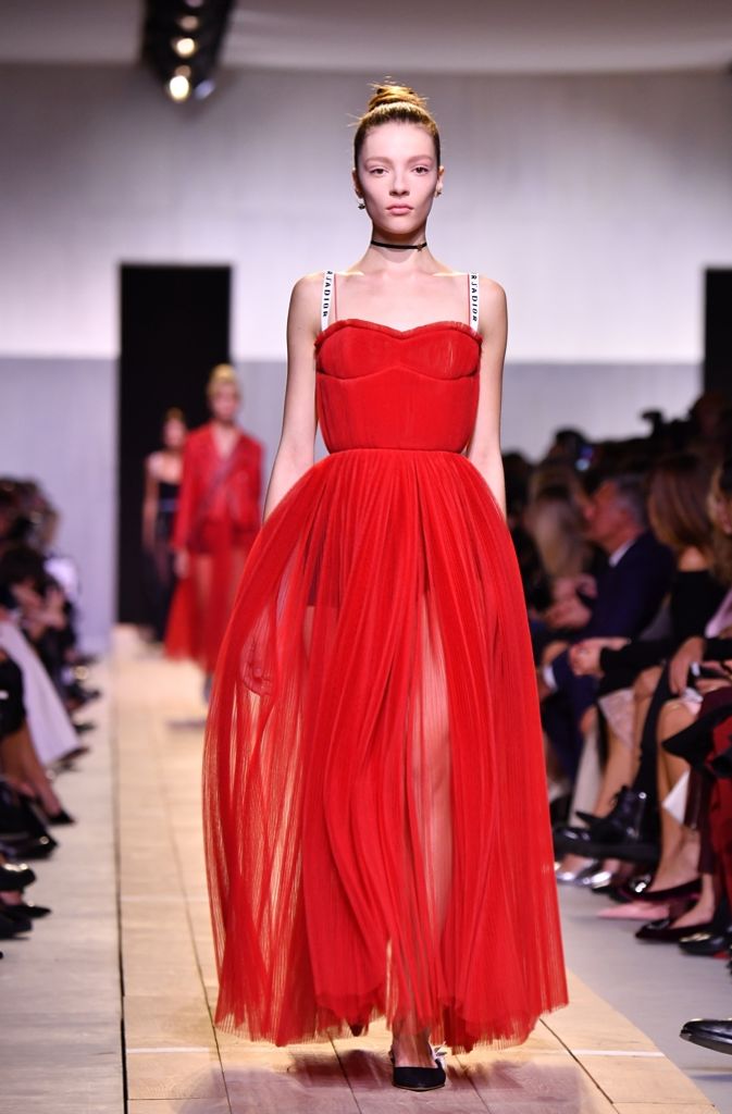 Christian Dior kombiniert das rote Kleid mit transparentem Rock mit schwarzen Accessoires.