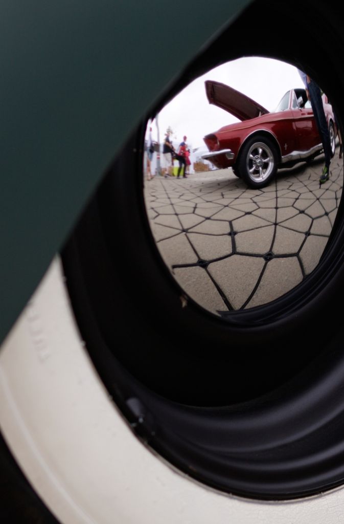 Ein roter Mustang spiegelt sich in der Radkappe eines anderen Wagens.
