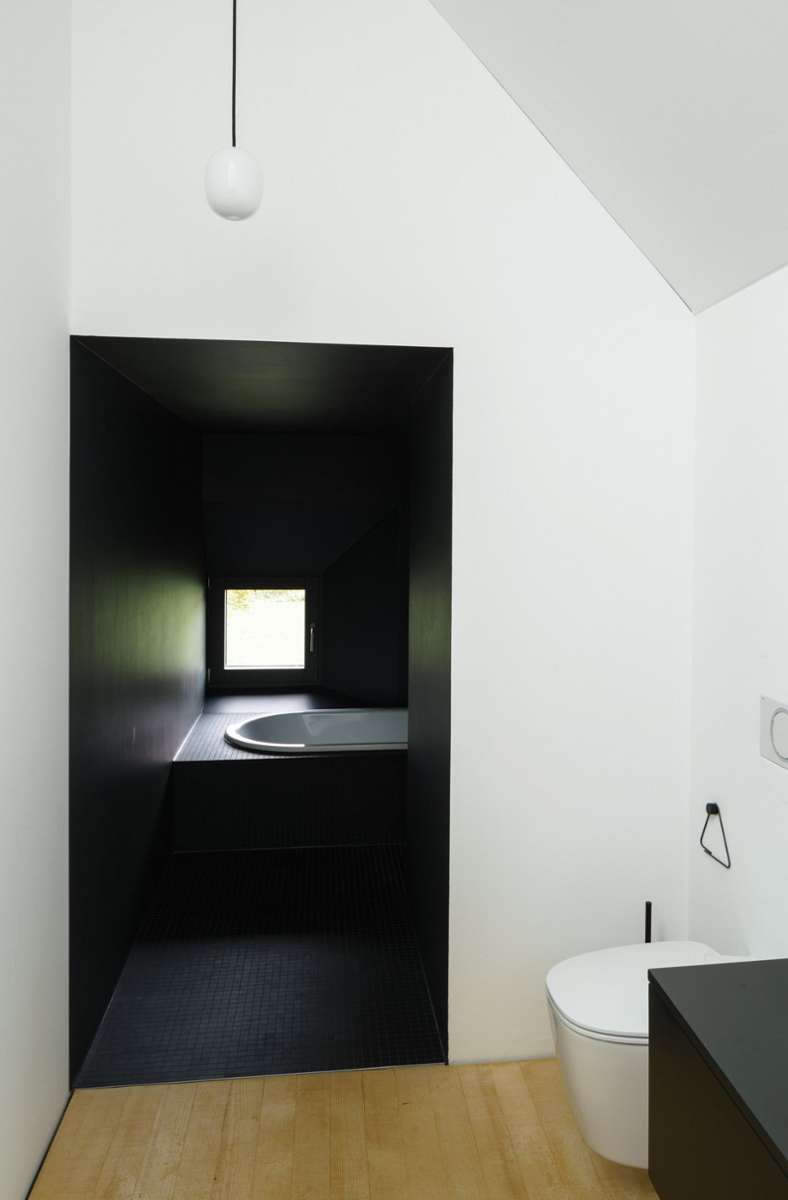 Elternbadezimmer mit Badewannen-Höhle und kleinem quadratischen Fenster für Ausblicke.