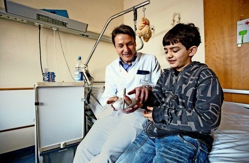 Chefarzt Thomas Ebinger vom Karl-Olga-Krankenhaus und   der schwer verletzte Farzad, der     seine Hand nun wieder gebrauchen kann. Foto: Michael Steinert