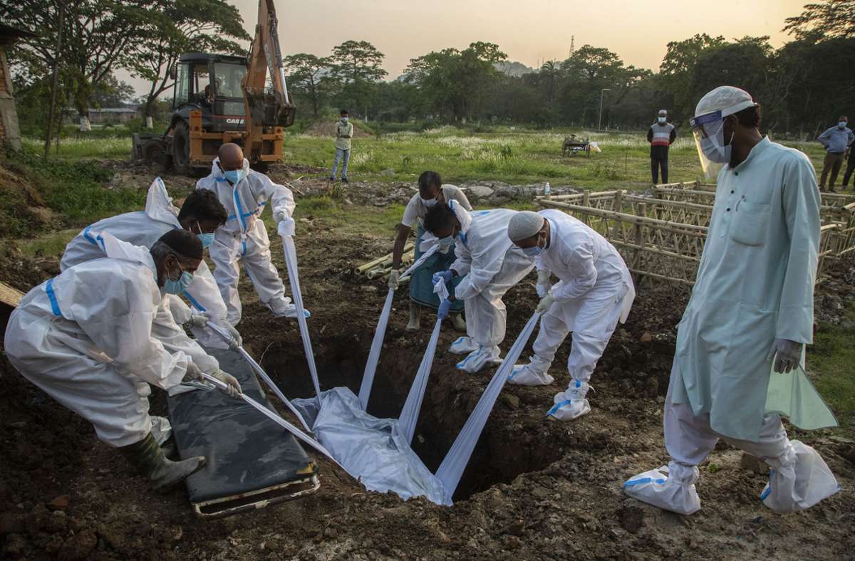 Gauhati: Angehörige und städtische Mitarbeiter in Schutzanzügen begraben den Körper einer Person, die an Covid-19 gestorben ist. Anupam Nath/AP/dpa