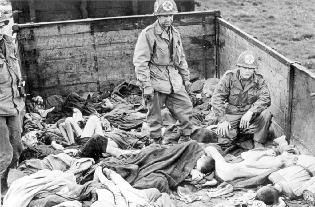 US-Soldaten stehen nach der Befreiung des KZ Dachau auf einem Waggon mit ermordeten Häftlingen