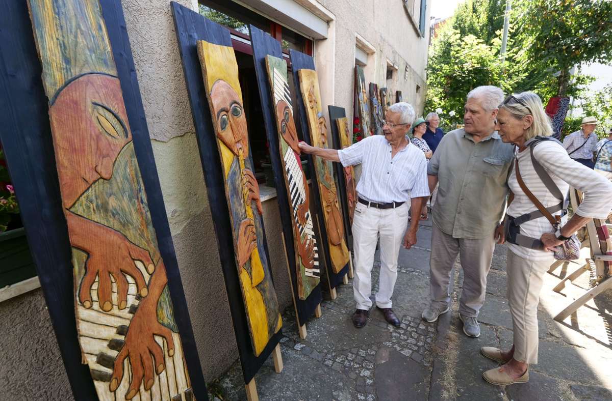 Walter Hörnstein (links) zeigt Besuchern seine Holzreliefs. Foto: Simon Granville/ 