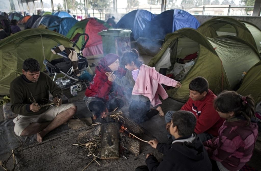 Flüchtlinge sitzen um ein Lagerfeuer im Zeltlager bei Idomeni.