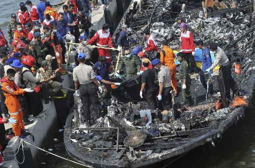 Rettungskräfte suchen in Jakarta auf einem Holzboot nach Opfern. Bei dem Brand sind am Sonntag mindestens 23 Menschen ums Leben gekommen. Foto: AP