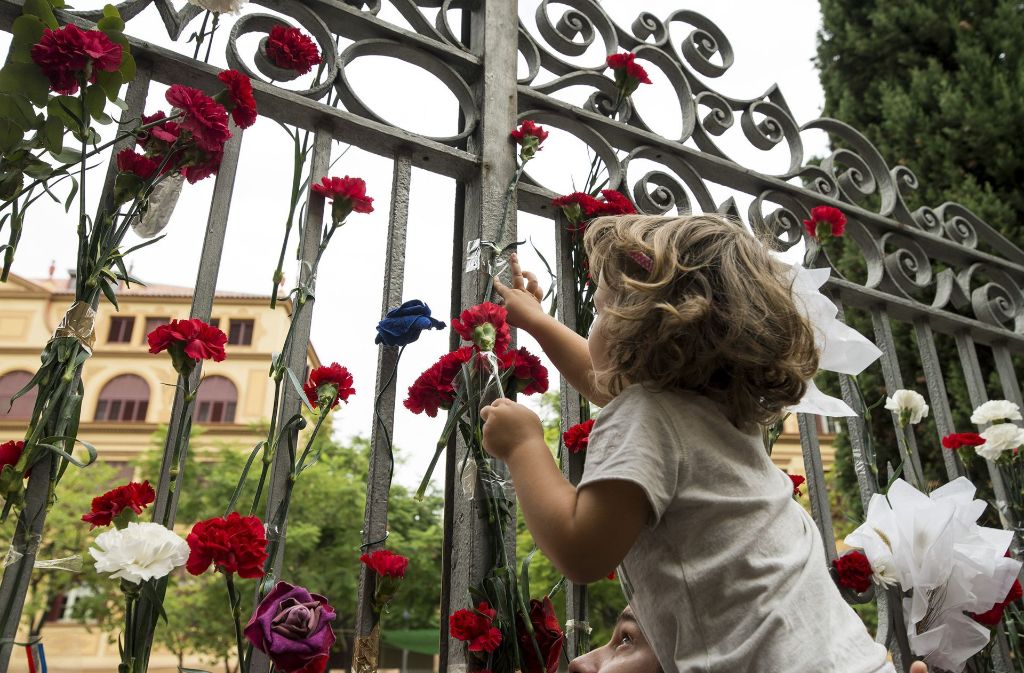Ein kleines Mädchen hängt Blumen an das Gitter einer Schule in Barcelona, die während des Referendums von Polizisten mit Gewalt blockiert worden war.