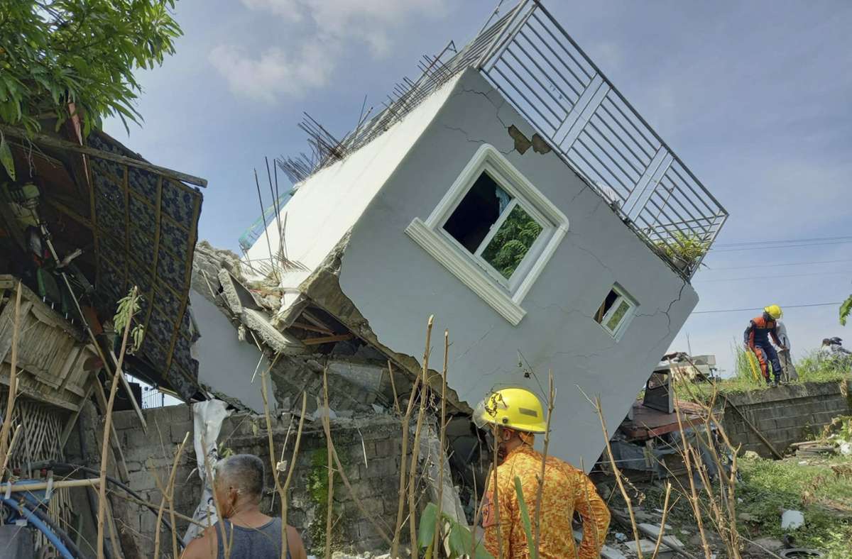 Rettungskräfte stehen vor einem eingestürzten Wohngebäude in Ilocos Sur.