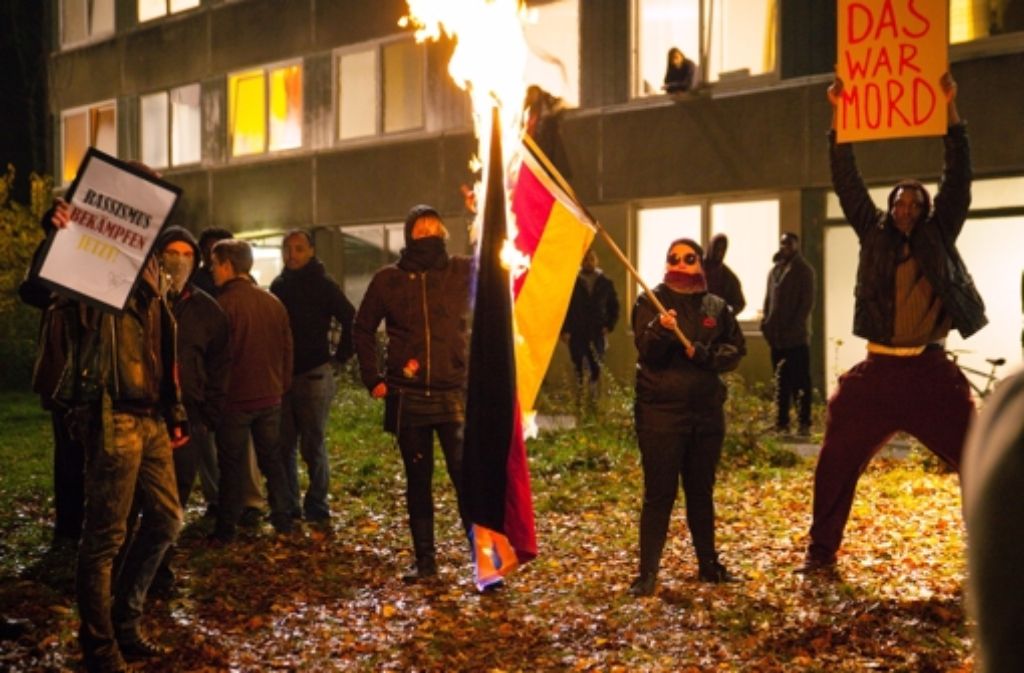 Aus Protest gegen den Tod des Opfers wird die deutsche Flagge wird vor dem Asylbewerberheim angezündet.