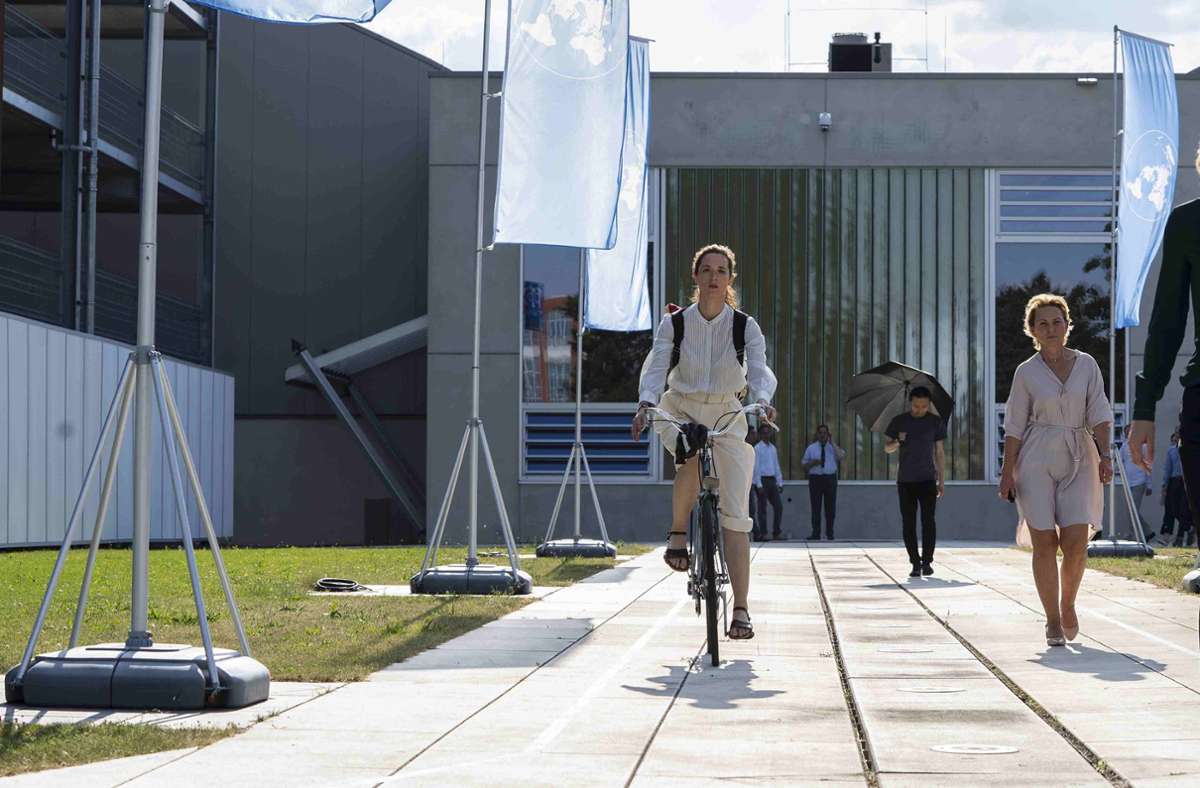 Larissa Meybach (Friederike Becht) auf dem Fahrrad vor dem provisorisch nach Berlin verlegten Internationalem Gerichtshof