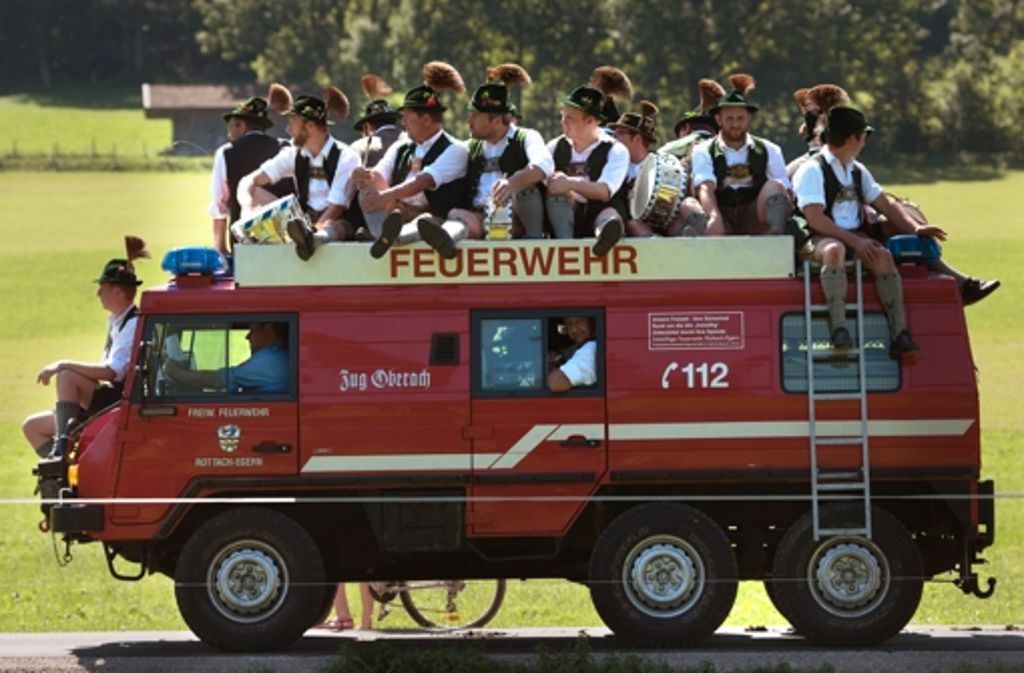 Am Rosstag am Tegernsee im August lässt sich eine bayrische Musikkapelle auf einem Feuerwehrauto von A nach B fahren.