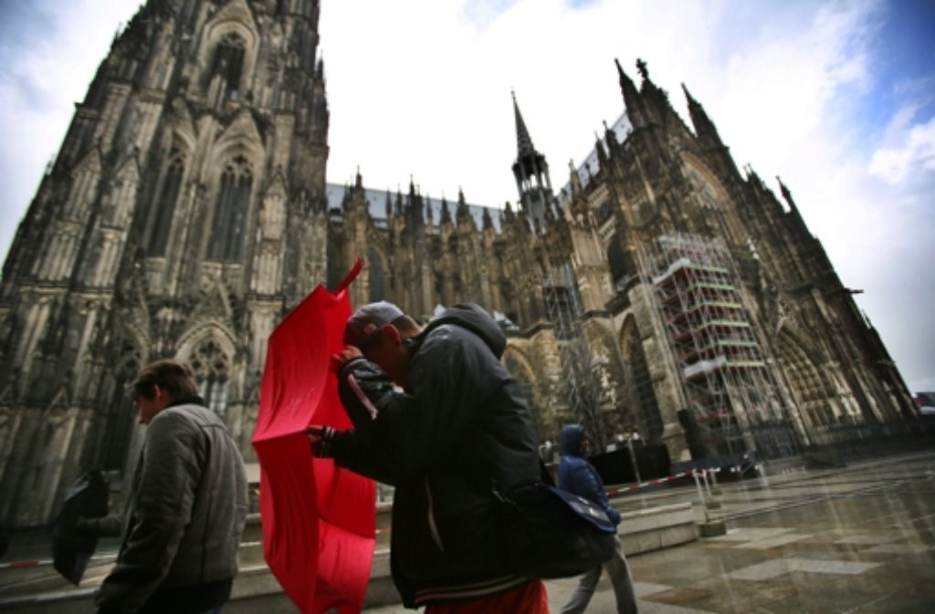 Touristen gehen in Köln (Nordrhein-Westfalen) am Dom vorbei.