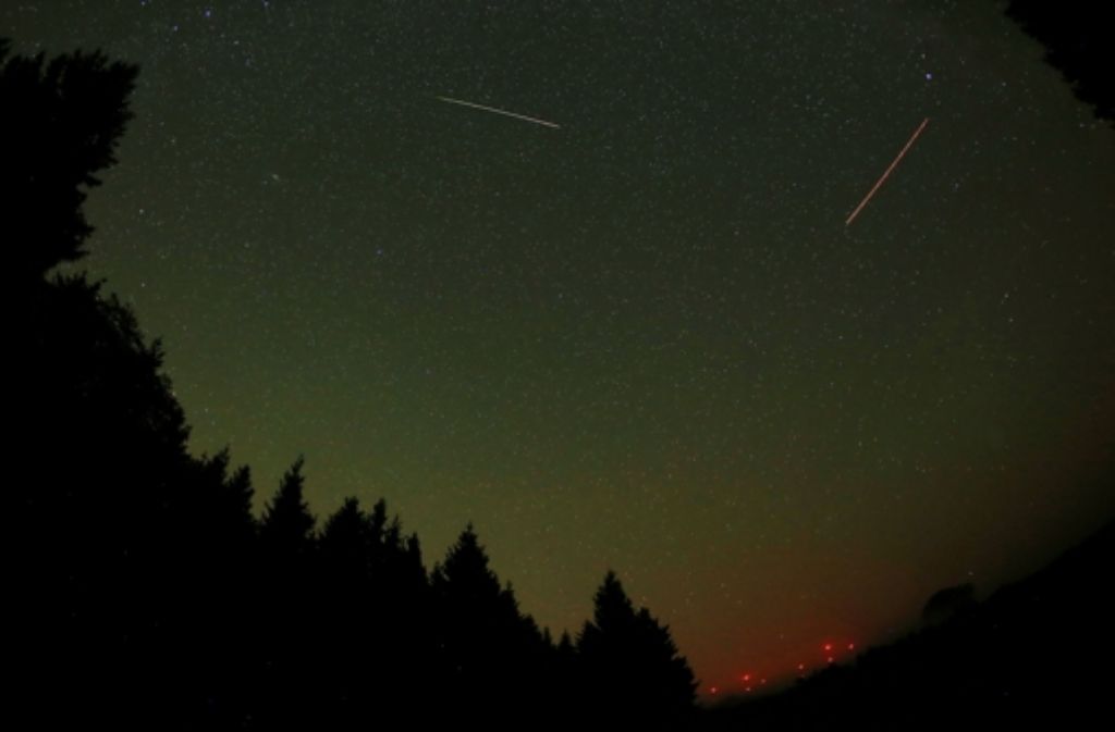 In der Eifel ist eine Sternschnuppe am Himmel neben der Leuchtspur eines Flugzeuges (r.) zu sehen.