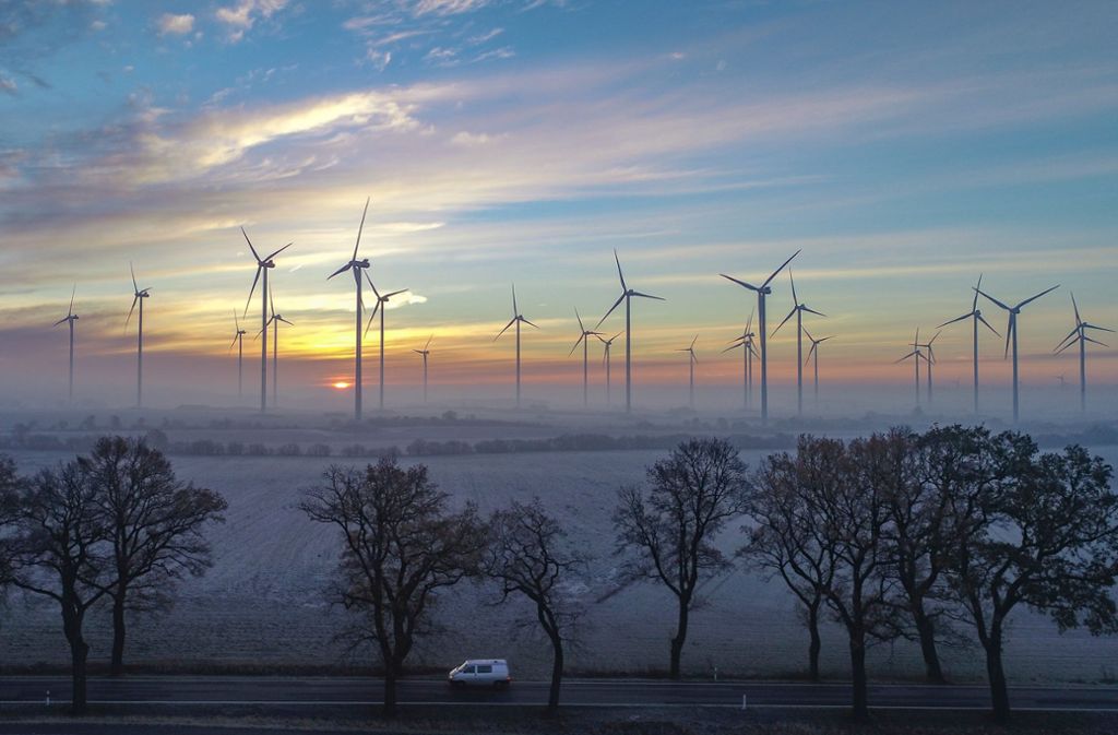 Hinter Wolkenschleiern leuchtete der Sonnenaufgang über der diesigen Landschaft mit dem Windenergiepark „Odervorland“ in Brandenburg.