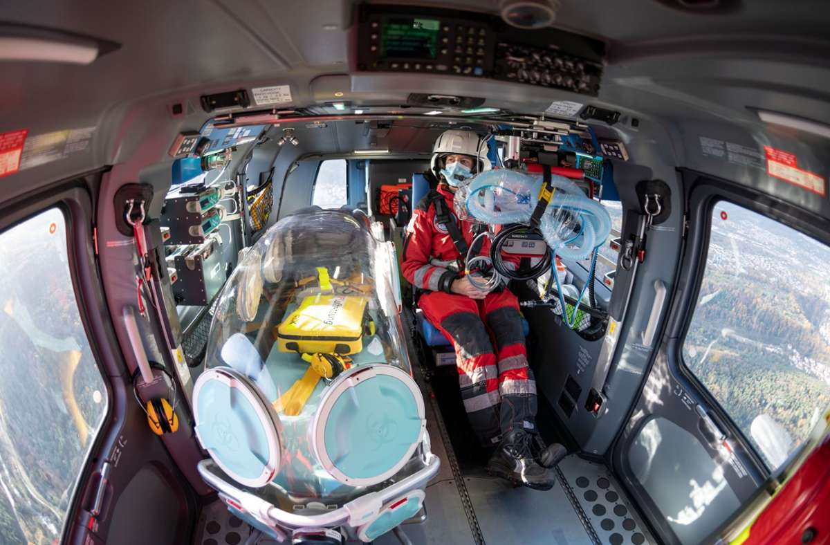 Die Notärztin Gerhild Gruner sitzt im Helikopter neben einer gläsernen Box, einem sogenannten Epishuttle. Sie ermöglicht es, Patienten wie in einer Isolierstation zu transportieren und schützt die Crew.
