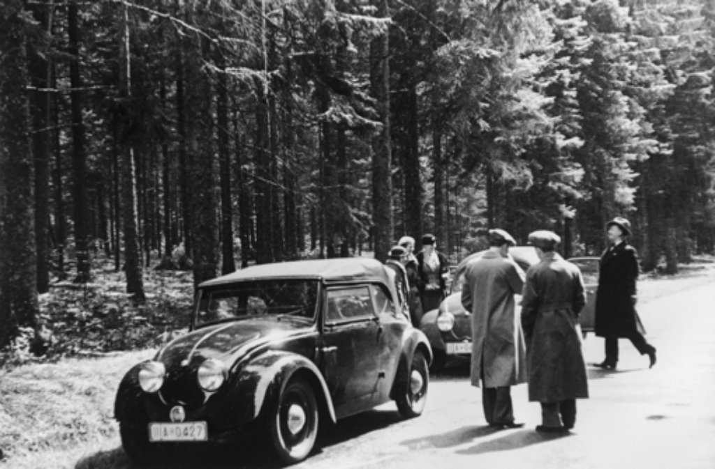 Das Werksfoto zeigt einen links Porsche Typ 60 (V2) und rechts einen Porsche Typ 60 (V1) bei einer Testfahrt an 1936. Daneben stehen: Maria Reimspiess, Waltraud Reitz, Sybille Reitz, Herbert Kaes, Ferry Porsche und Wolfgang Reitz (von links).