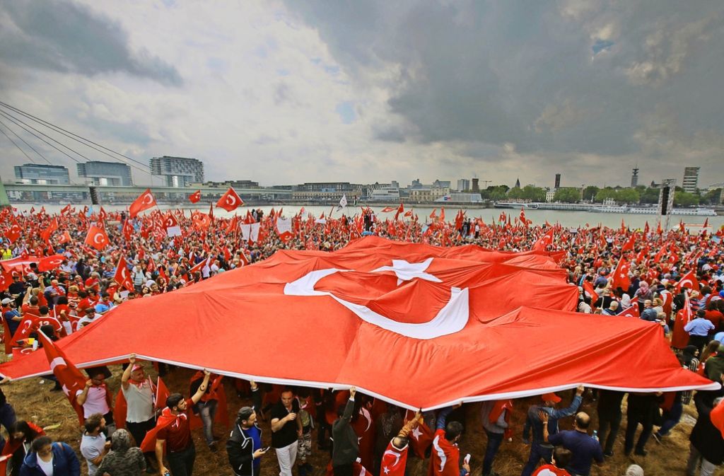 Eingedeckt mit türkischen Nationalflaggen in jeglicher Größe stellen sich die Menschen am Rheinufer hinter den Staatspräsidenten.
