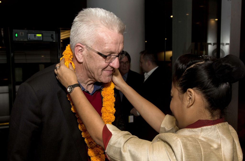Eine Frau heißt den baden-württembergischen Ministerpräsident Winfried Kretschmann in Pune (Indien) willkommen.