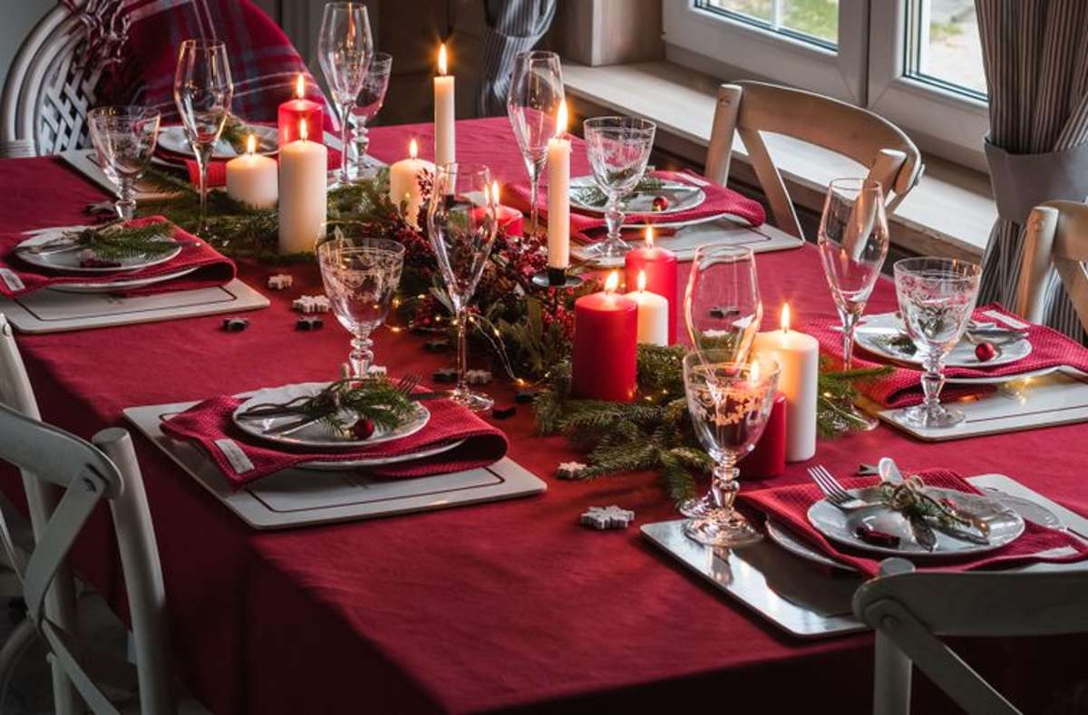 Eine festliche Tannengirlande mit zahlreichen Kerzen auf einer schönen roten Tischdecke.