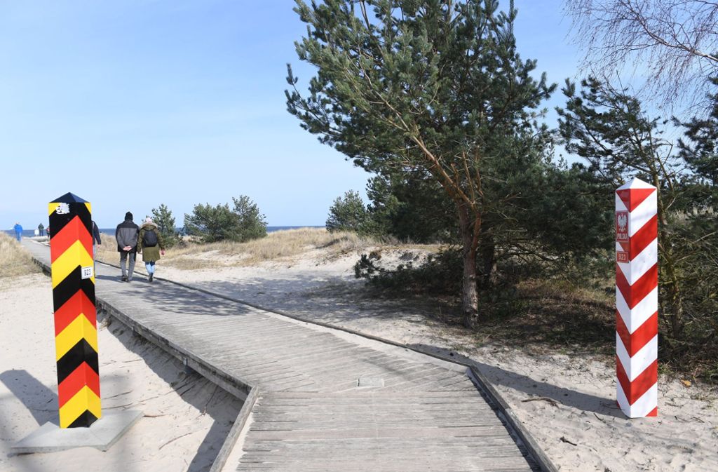 Touristen laufen auf der Insel Usedom zwischen den Grenzpfeilern an der deutsch-polnischen EU-Binnengrenze.