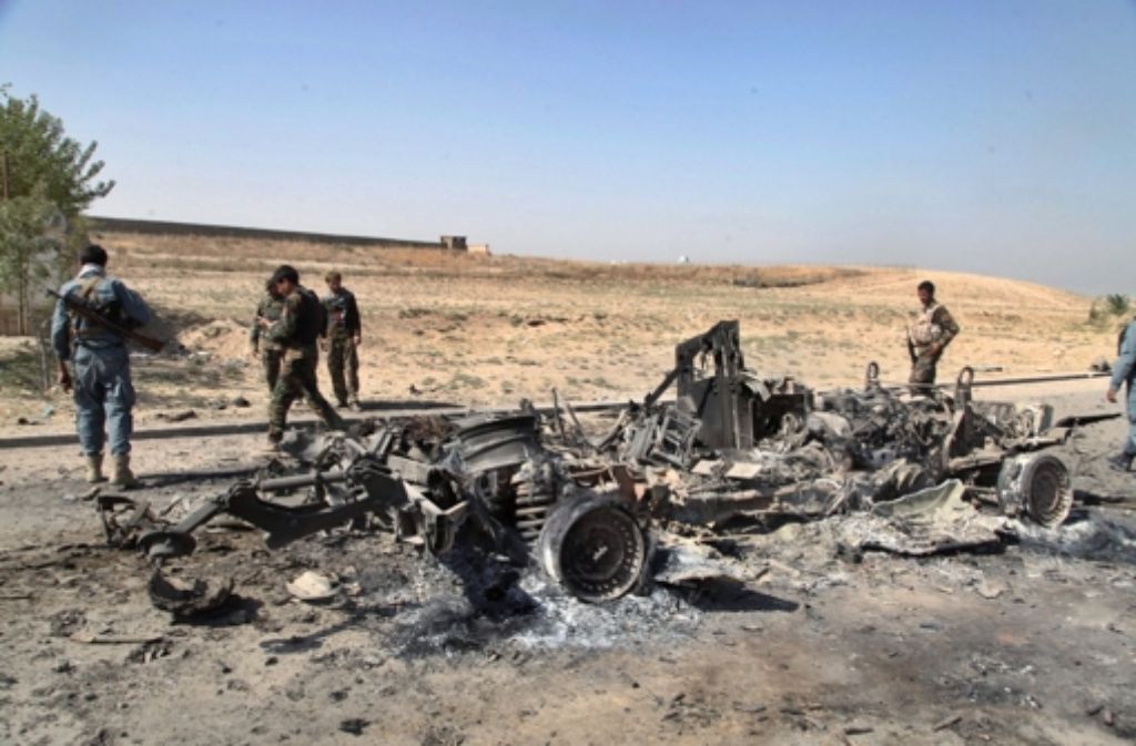 Afghanische Sicherheitskräfte inspizieren ein ausgebranntes Wrack. Foto: dpa