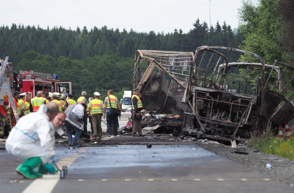 Experten der Spurensicherung untersuchen die ausgebrannten Überreste des Unglücksbusses.